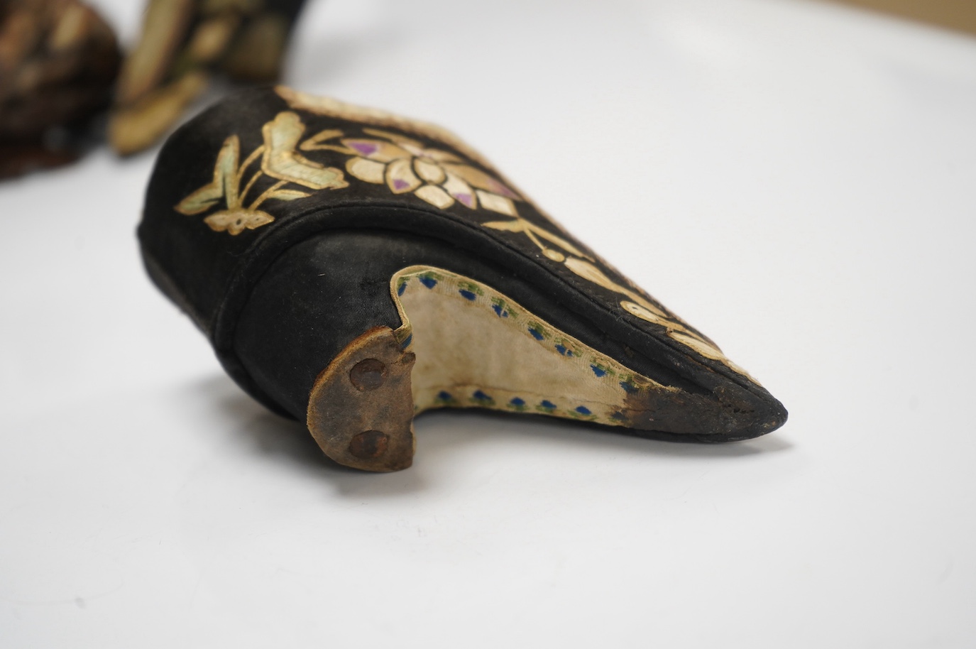 A pair of Chinese black silk embroidered ‘foot bound’ ladies shoes and a soapstone group of HeHe Erxian on carved stand, soapstone carving on stand 8cm high (3). Condition - fair to good